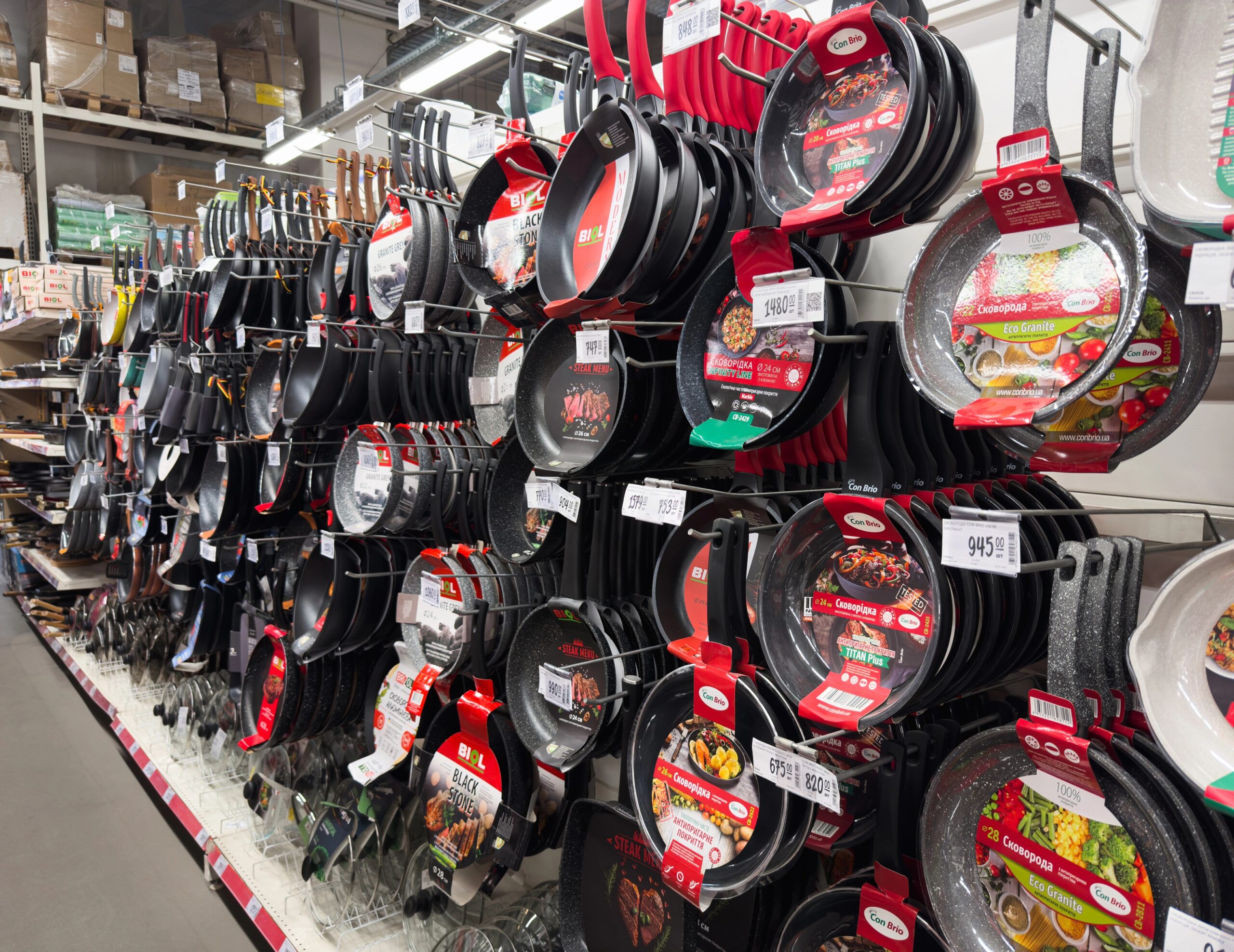 Store shelf display of various non-stick frying pans and cookware in a kitchenware aisle