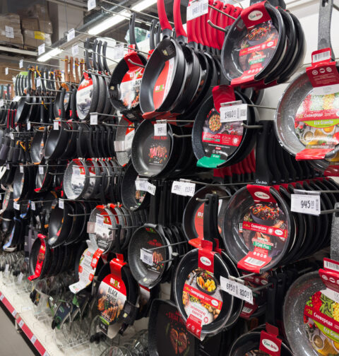 Store shelf display of various non-stick frying pans and cookware in a kitchenware aisle