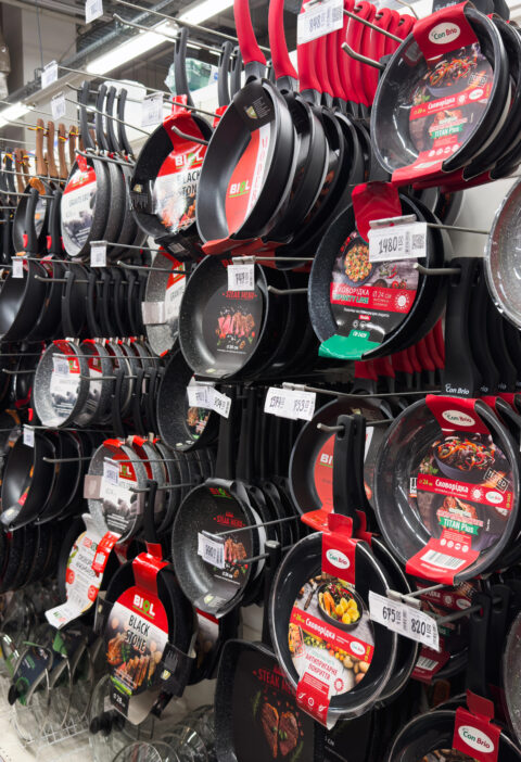 Store shelf display of various non-stick frying pans and cookware in a kitchenware aisle