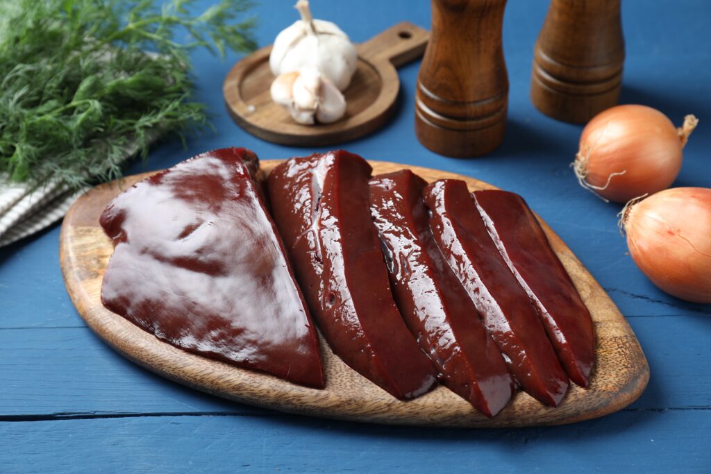 Cut raw beef liver with onions, garlic, dill and spices on blue wooden table, closeup (<a href="https://depositphotos.com/?ref=26541392&utm_source=linkCopy&utm_medium=referral" target="_blank" rel="noopener noreferrer">Stock Depositphotos</a>)