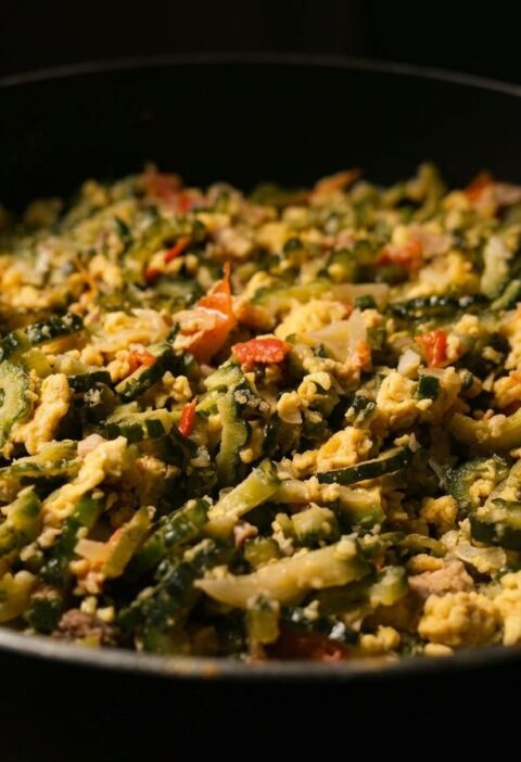 A pan of stir-fried bitter melon with scrambled eggs, tomatoes, onions, and garlic