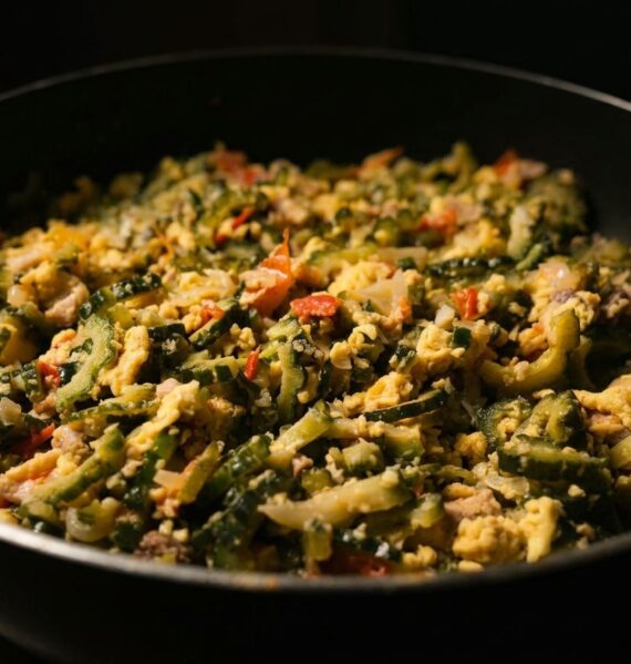 A pan of stir-fried bitter melon with scrambled eggs, tomatoes, onions, and garlic